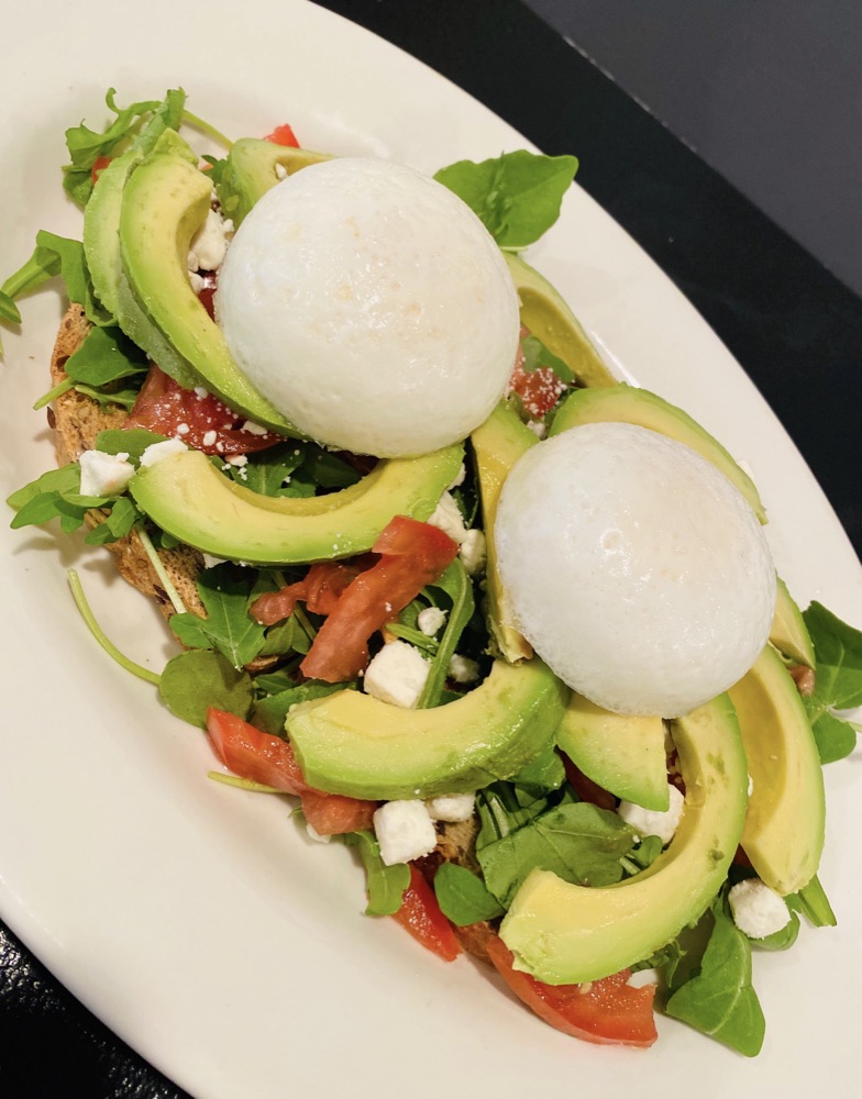 Avocado with poached eggs over greens
